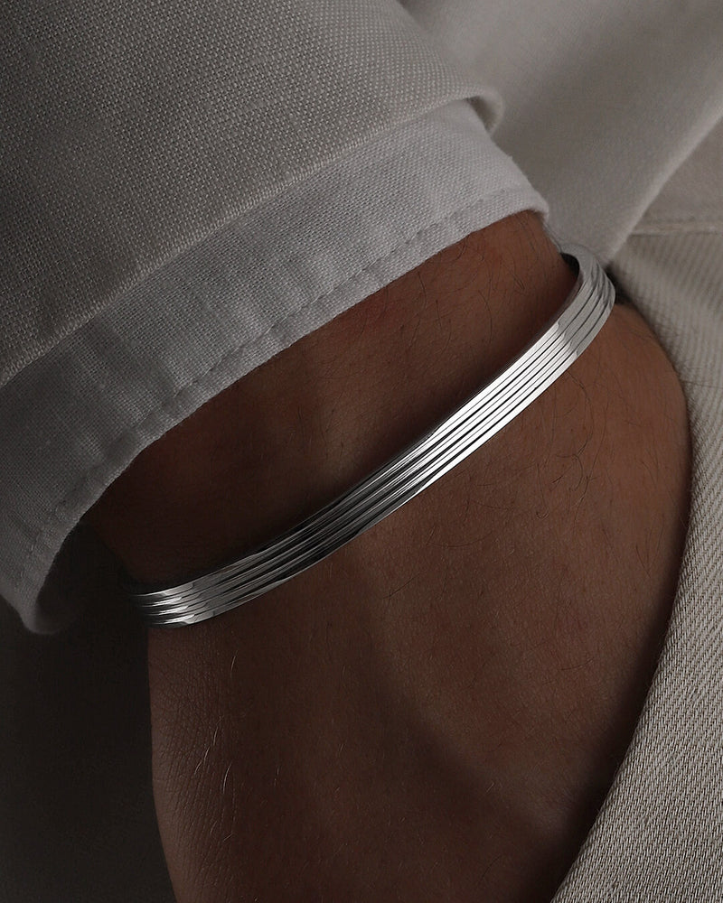 A polished stainless steel bangle in silver from Waldor & Co. One size. The model is Avant Bangle Polished