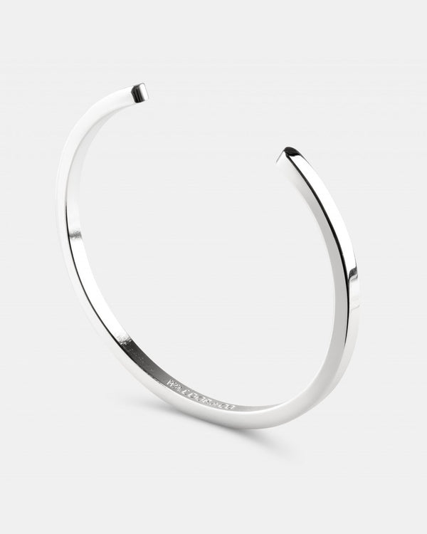A polished stainless steel bangle in silver from Waldor & Co. One size. The model is Square Bangle Polished