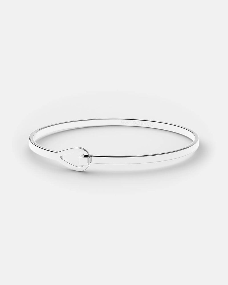 A polished stainless steel bangle in silver from Waldor & Co. The model is Signature Bangle Polished 