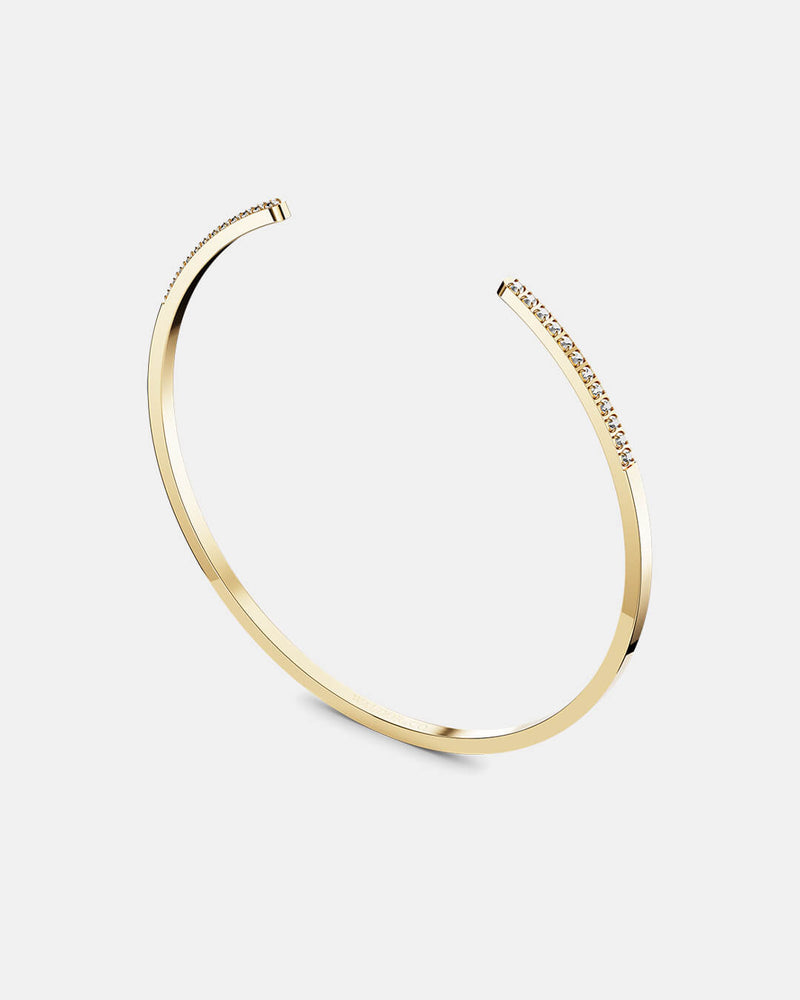 A polished stainless steel bangle in 14k gold from Waldor & Co. One size. The model is Acme Bangle Polished.