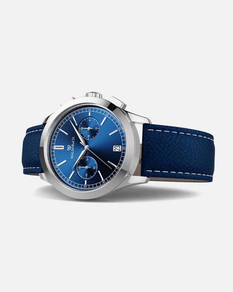 A round mens watch in rhodium-plated silver from Waldor & Co. with blue sunray dial and genuine blue leather strap. A second hand. Seiko movement. The model is Chrono 39 Sardinia 39mm.