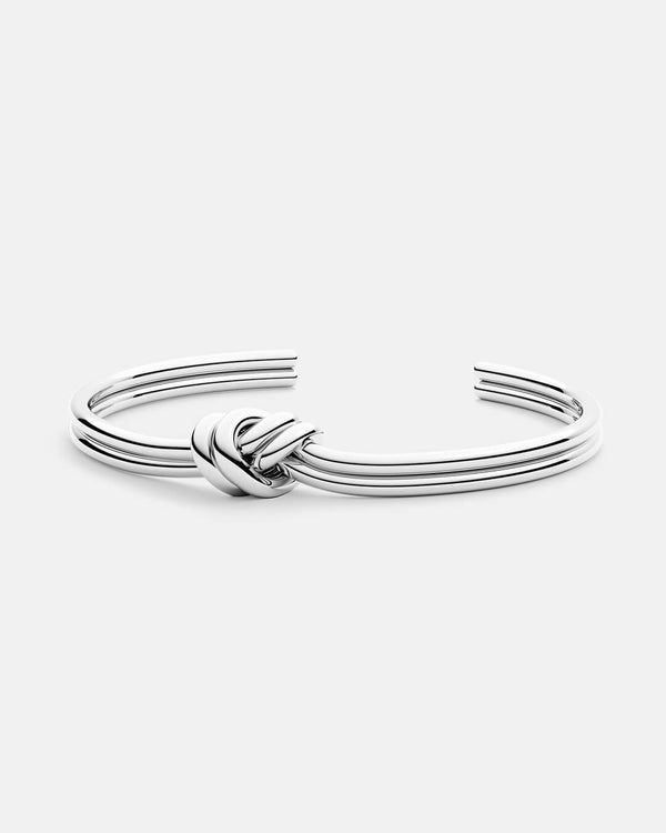 Polished A polished stainless steel bangle in silver from Waldor & Co. One size. The model is Dual Knot Bangle Polished