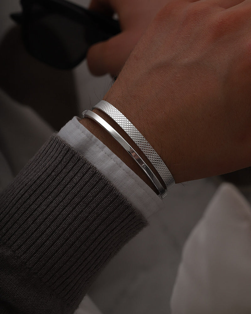 A polished stainless steel bangle in silver from Waldor & Co. One size. The model is Grid Bangle Polished.