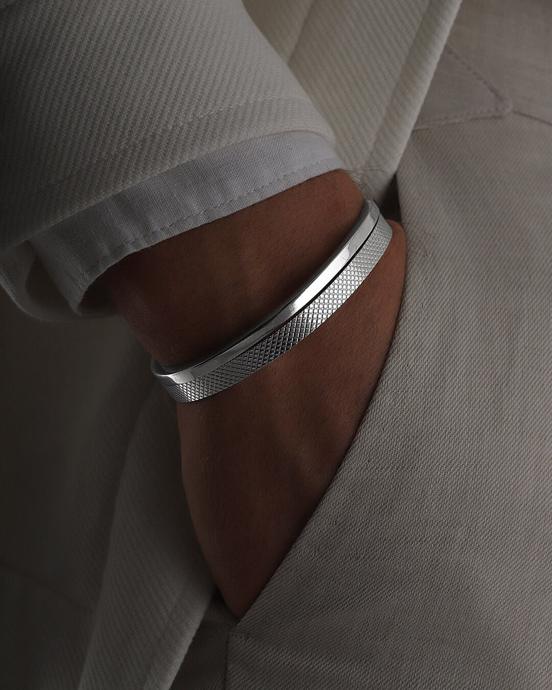 A polished stainless steel bangle in silver from Waldor & Co. One size. The model is Grid Bangle Polished.