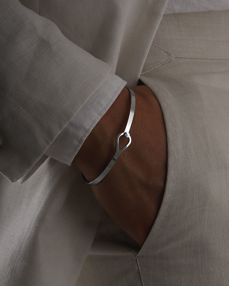 A polished stainless steel bangle in silver from Waldor & Co. The model is Signature Bangle Polished