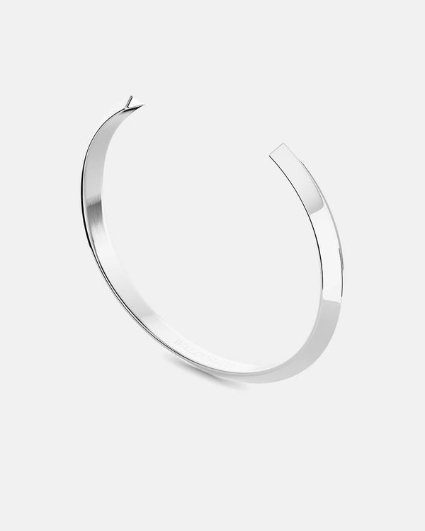 A polished stainless steel bangle in silver from Waldor & Co. One size. The model is Triangle Bangle Polished